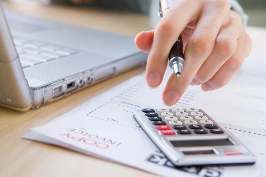 Accountant using calculator with invoice